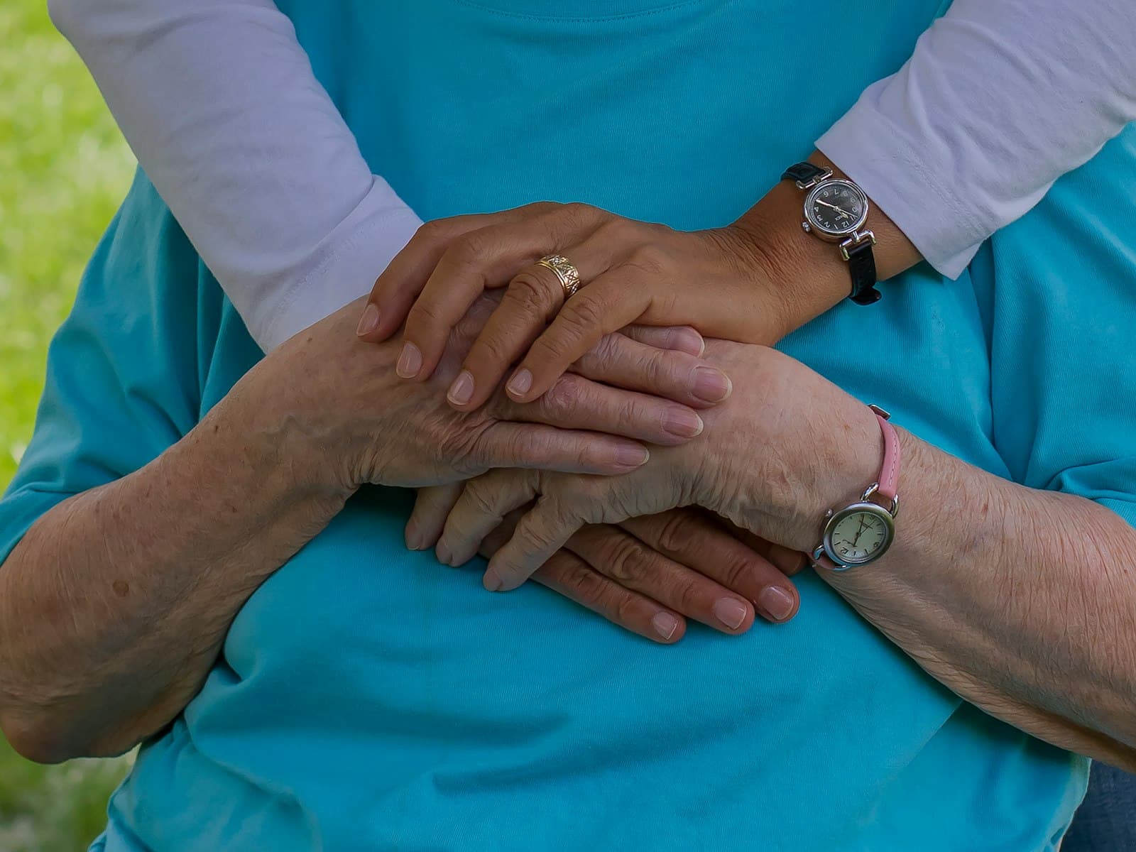 A quiet moment between a caregiver and the person they support, hands resting together.