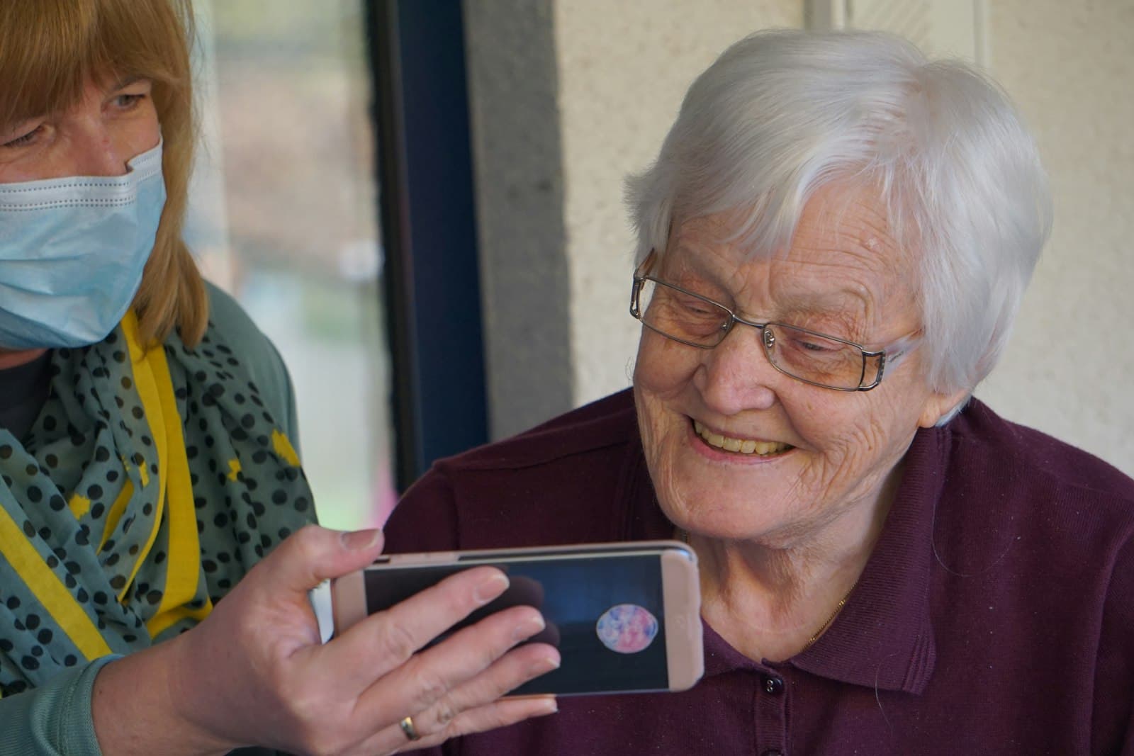 Grace smiling at a smartphone screen during a video call with family.